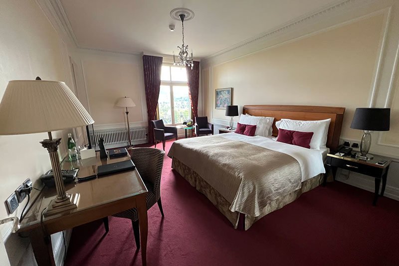 Double bed in a luxury room with a red carpet and a window to light to room